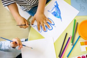 Enfant dessinant l’empreinte de sa main pendant un atelier créatif Pitchoun’Art à Hourtin