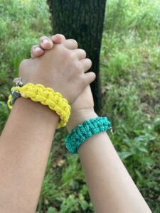 Bracelet de survie en paracorde réalisé et porté par deux enfants lors d’un atelier DIY créatif chez Pitchoun'Art à Hourtin dans le Médoc